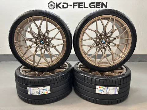 Background image for Original BMW 1000M 20/21 Zoll Sommerräder M2 G87 M3 G80 G81 M4 G82 M Performance Kreuzspeiche M 1000 Alufelgen Goldbronze matt